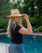 Model wearing Macho Natural Unisex Straw Cowboy Hat with Adjustable Wire Rim handmade woven raffia in a solid hue of natural straw color in a structured crown style with open weave pattern for breathability and pliable wire rim with matching twisted cord hat band - Shebobo