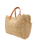 Side view Madeline Natural XL Crochet Raffia Straw Basket Shoulder Bag with Pockets handmade raffia palm fiber in a solid hue of natural straw color with crochet horizontal subtle band texture, round boucle nub edges, oversized external pockets, and leather handles - Shebobo