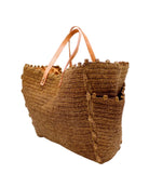 Side view Madeline Tobacco XL Crochet Raffia Straw Basket Shoulder Bag with Pockets handmade raffia palm fiber in a solid hue of tobacco dark/cinnamon/brown with crochet horizontal subtle band texture, round boucle nub edges, oversized external pockets, and leather handles - Shebobo