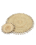 Detail view Makena Round Raffia Straw Coasters & Placemats with Cowrie Shell Edge Set of 6 handmade woven raffia palm fiber in a solid hue of natural straw color with coiled loop texture discs with cowrie shell edge embellishment set of six - Shebobo