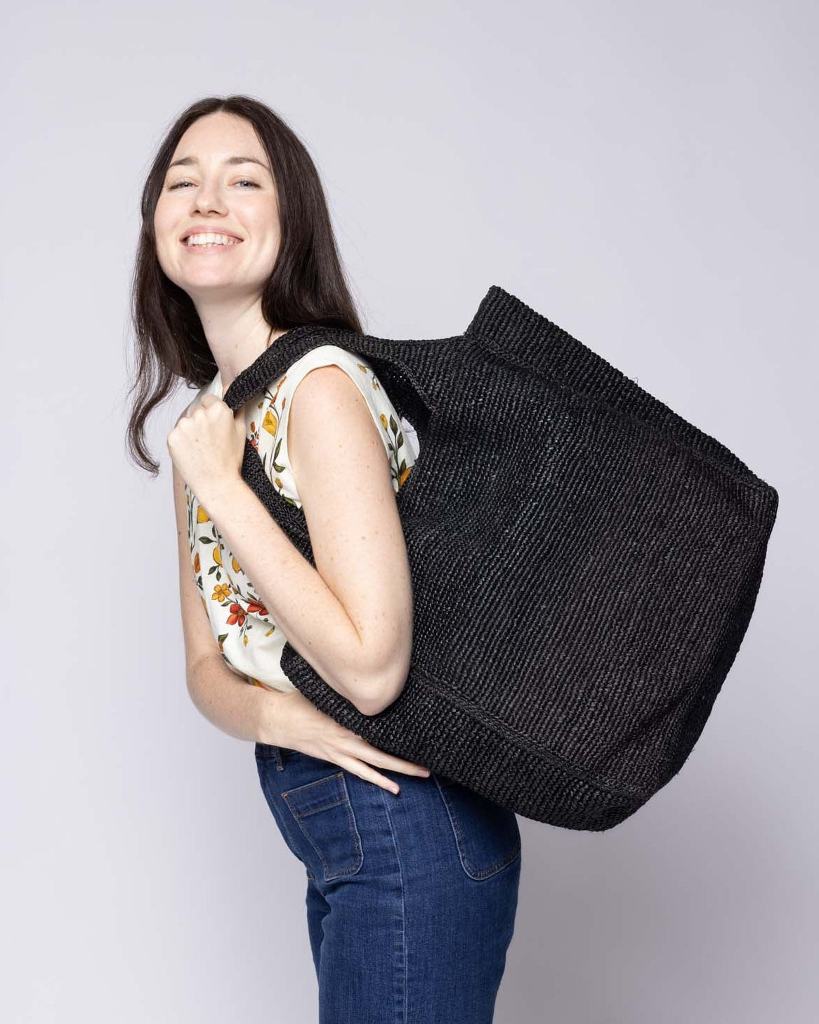 Model wearing Mamie XL Crochet Straw Basket Handbag handmade crochet natural raffia palm fiber in a solid hue of black purse beach bag - Shebobo