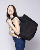 Model wearing Mamie XL Crochet Straw Basket Handbag handmade crochet natural raffia palm fiber in a solid hue of black purse beach bag - Shebobo