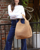 Model wearing Mamie XL Crochet Straw Basket Handbag handmade crochet natural raffia palm fiber in a solid hue of cappuccino tea/light/brown purse beach bag - Shebobo