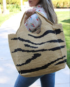Model wearing Mamie XL Crochet Straw Basket Handbag handmade crochet natural raffia palm fiber in a two tone natural and black zebra stripe pattern purse beach bag - Shebobo