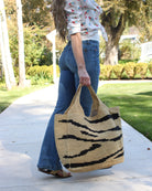 Model wearing Mamie XL Crochet Straw Basket Handbag handmade crochet natural raffia palm fiber in a two tone natural and black zebra stripe pattern purse beach bag - Shebobo