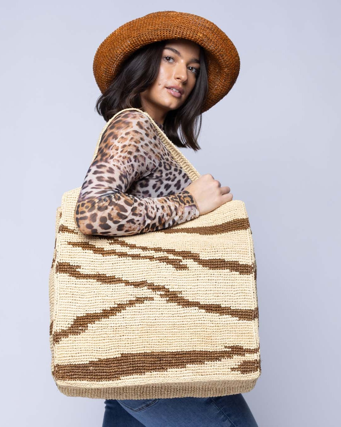 Model wearing Side view Mamie XL Crochet Straw Basket Handbag handmade crochet natural raffia palm fiber in a two tone natural straw color and tobacco dark/cinnamon/brown zebra stripe pattern purse beach bag - Shebobo