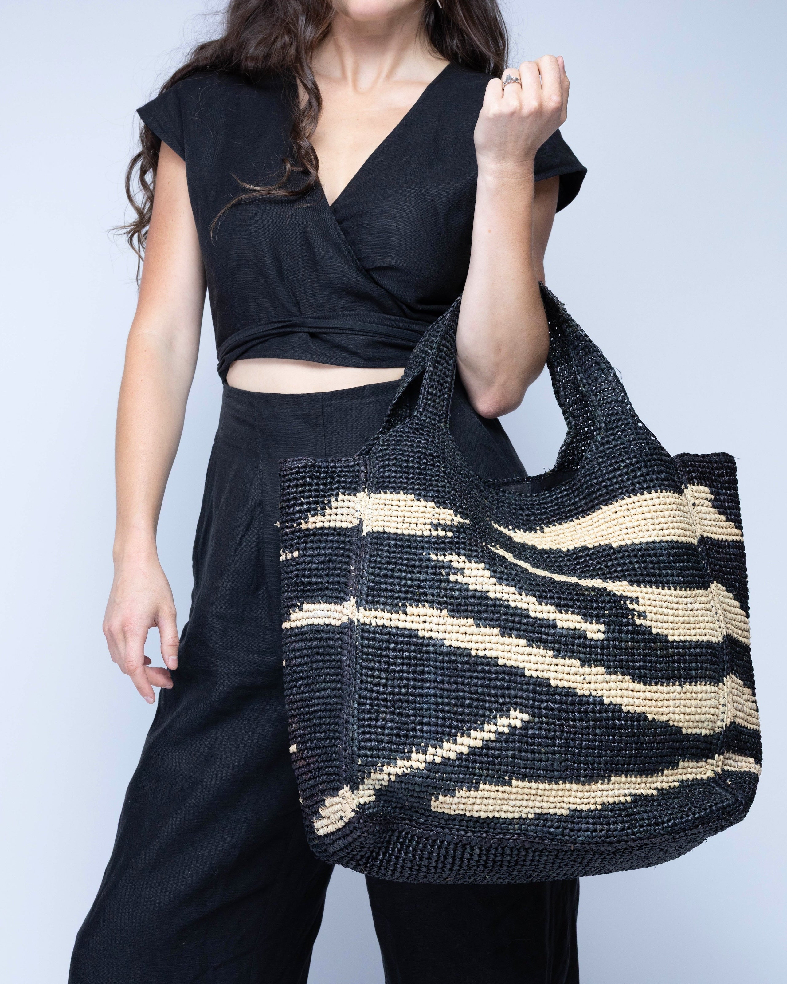 Model wearing Mamie XL Crochet Straw Basket Handbag handmade crochet natural raffia palm fiber in a two tone black and natural straw color zebra stripe pattern purse beach bag - Shebobo