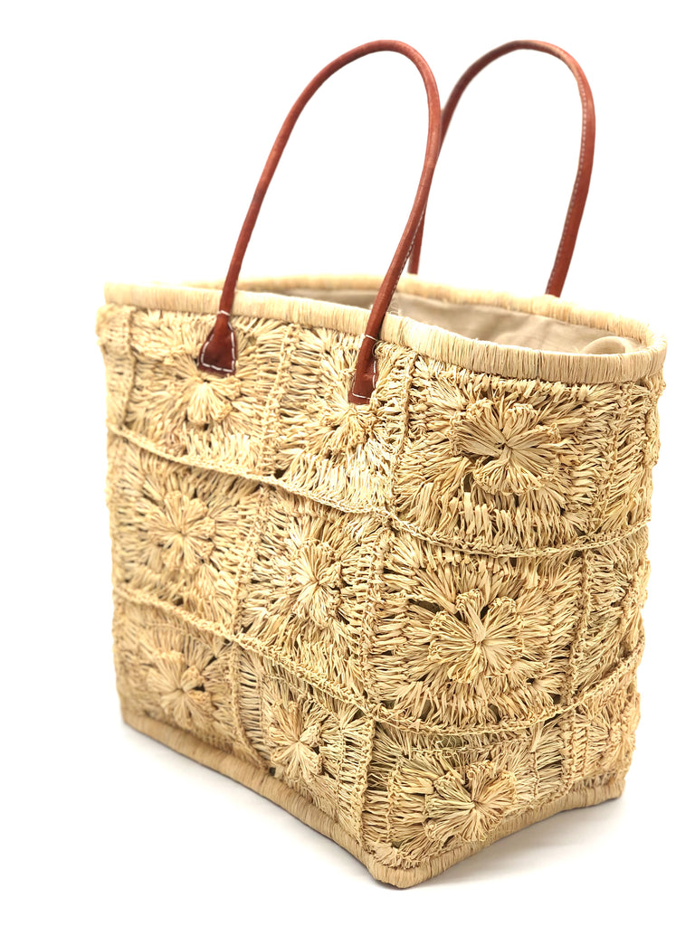 Side view Marie Flower Crochet Straw Basket Bag handmade natural raffia palm fiber woven into a geometric grid of squares with a central flower per square similar to a granny square pattern handbag tote with leather handles - Shebobo