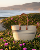 Marina Racing Stripe Small Straw Tote Bag handmade loomed natural raffia palm fiber in a solid hue of natural straw color with three horizontal bands of black making a pinstripe pattern across the top third of the bag with matching cross-stitch edging, leather handles and accents beach bag handbag - Shebobo 