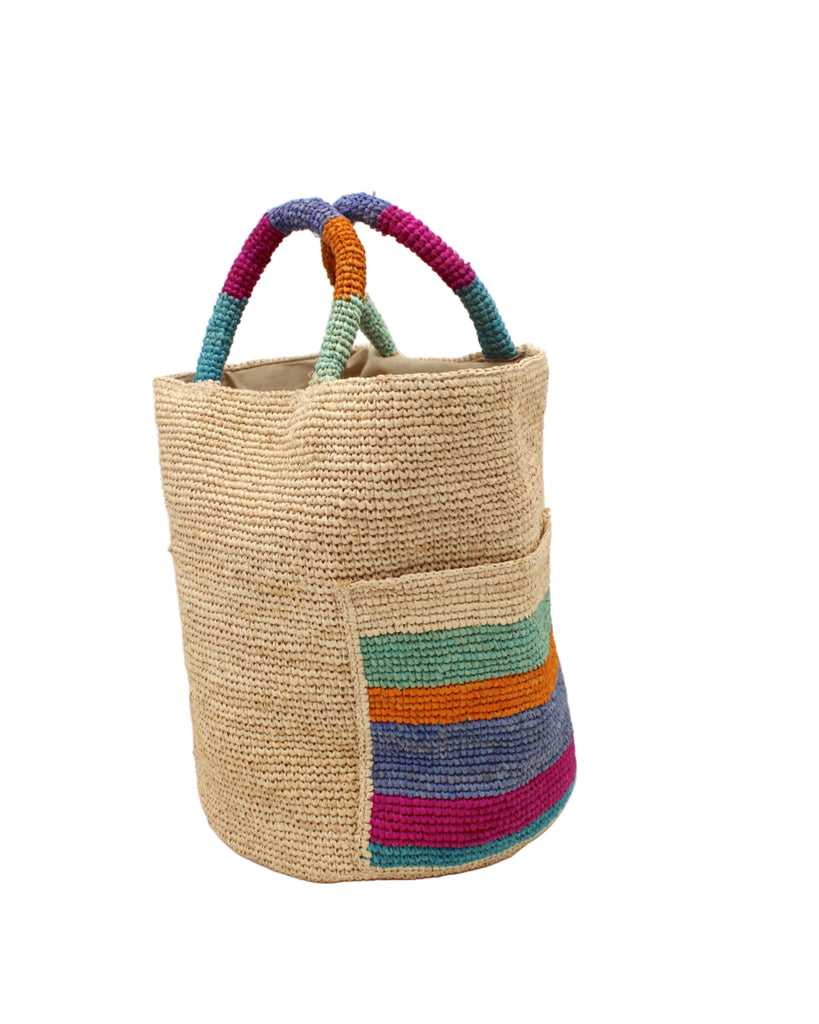 Side view Milos Caribbean Stripes Crochet Straw Basket Handbag with Pockets handmade natural raffia palm fiber in a solid hue of natural straw color on the body of the bag with multicolor wide stripe pattern of turquoise blue/green, fuchsia hot/bright/barbie/pink, denim retro/light/blue, saffron yellow/orange, and seafoam light/blue/green on both handles as well as two large external pockets tote bag - Shebobo