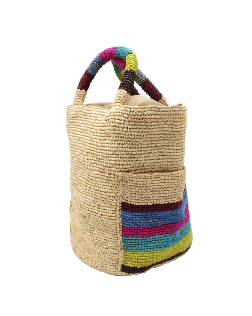 Side view Milos Riviera Stripes Crochet Straw Basket Handbag with Pockets handmade natural raffia palm fiber in a solid hue of natural straw color on the body of the bag with multicolor wide stripe pattern of umberwine bordeaux/claret/deep/dark/red/purple, denim retro/light/blue, fuchsia hot/bright/barbie/pink, teal dark/blue/green, midori lime/neon/green, and black on both handles as well as two large external pockets tote bag - Shebobo