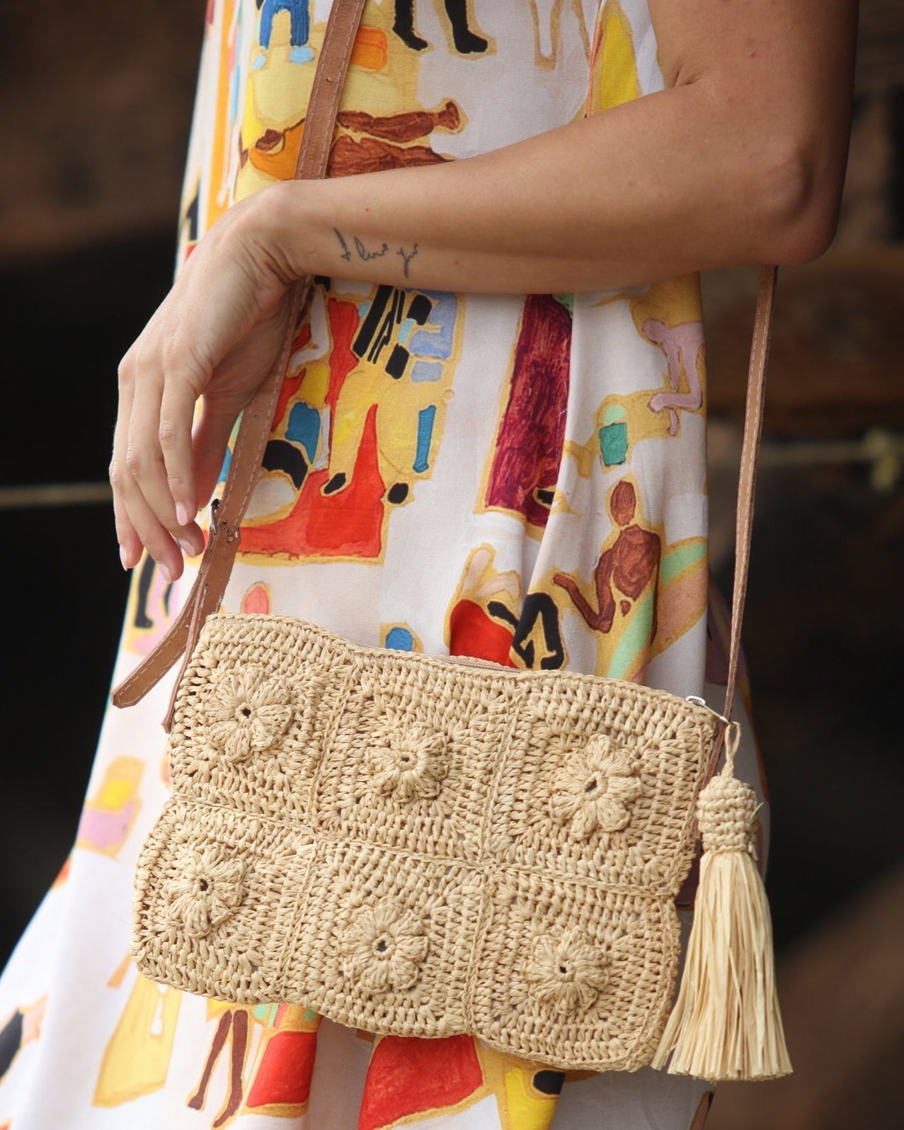 Model wearing Mimi handmade crochet granny square geometric square and floral pattern natural crochet crossbody bag straw purse with leather strap - Shebobo *dress by Kikisol
