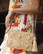 Model wearing Mimi handmade crochet granny square geometric square and floral pattern natural crochet crossbody bag straw purse with leather strap - Shebobo *dress by Kikisol