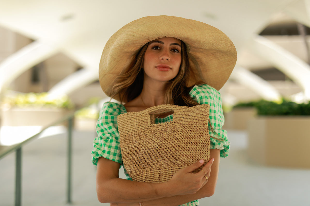 Model wearing Mini ConCon Crochet Straw Basket - Petite Crochet Bag handmade natural raffia palm fiber woven handbag - Shebobo (with Monica 7" Wide Brim Packable Straw Sun Hat)