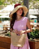Model wearing Mini ConCon Crochet Straw Basket - Petite Crochet Bag handmade natural raffia palm fiber woven handbag - Shebobo (with 7" Wide Brim Bordeaux Two Tone Packable Straw Sun Hat)