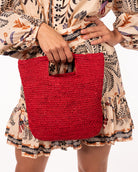 Model wearing Mini ConCon Crochet Petite Straw Basket handmade woven raffia palm fiber in a solid hue of red making a textured link pattern handbag purse small bag - Shebobo