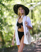 Model wearing Monica 7" Wide Brim Black Pinstripes Packable Straw Sun Hat handmade loomed raffia in wide bands of black with narrow bands of natural straw color create a striped swirl pattern - Shebobo