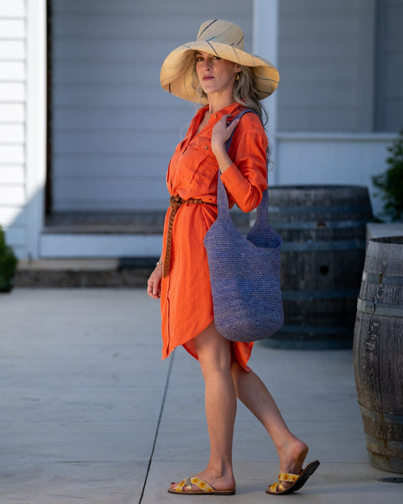 Model wearing Monica 7" wide brim natural and multicolor pinstripes packable raffia straw hat handmade loomed raffia in wide bands of natural straw color with narrow bands of dusk navy/dark/blue, turquoise blue/green, denim retro/light/blue, etc. create a stripe swirl pattern - Shebobo (with Kiki Crochet Crossbody Bag and Daisy Straw Sandal)