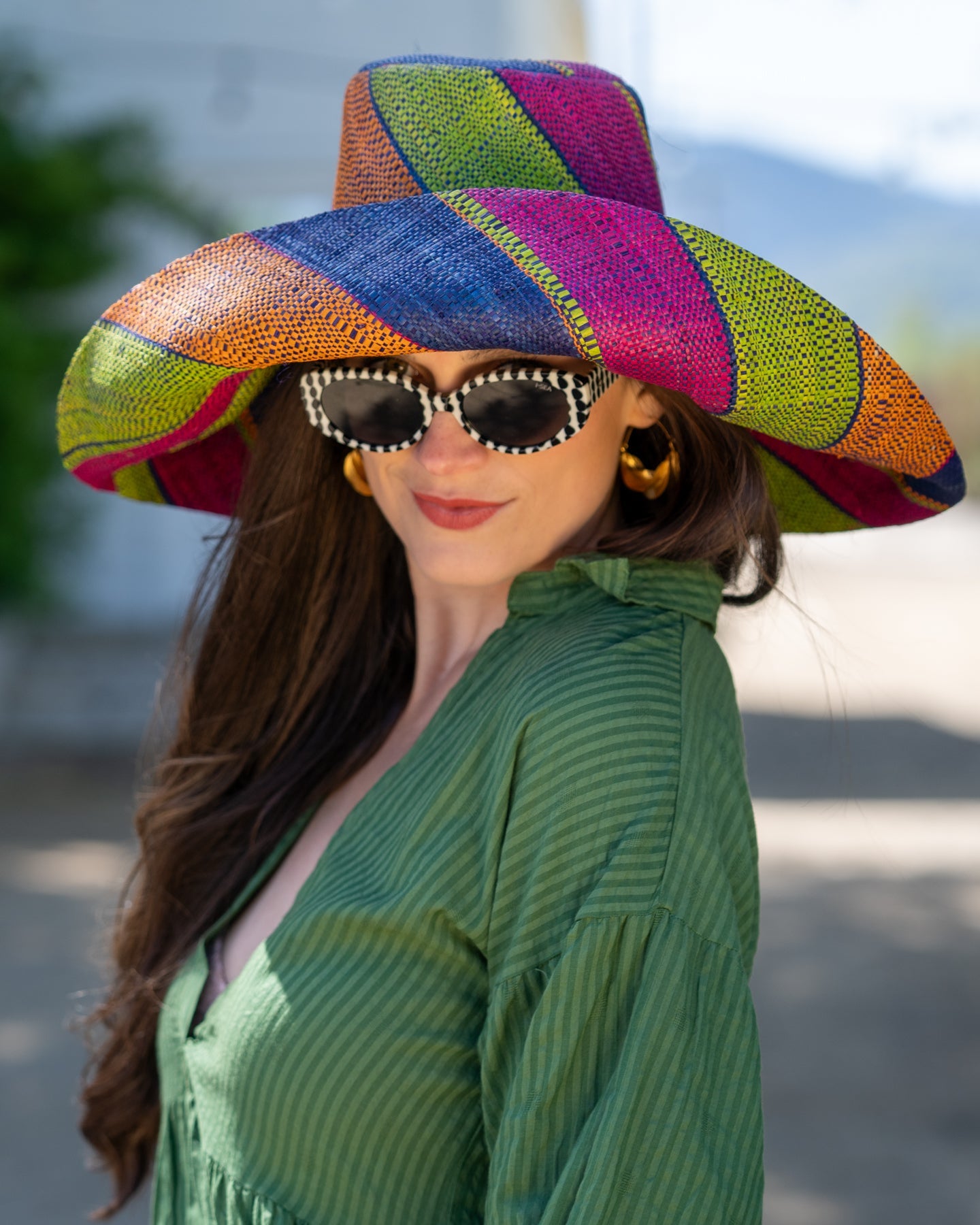 Model wearing Monica 7" Wide Brim Caribbean Swirl Multicolor Stripes Packable Straw Sun Hat Handmade loomed raffia in multi width bands of fuchsia pink, orange, dusk navy/dark/blue, and lime green create a swirl pattern - Shebobo