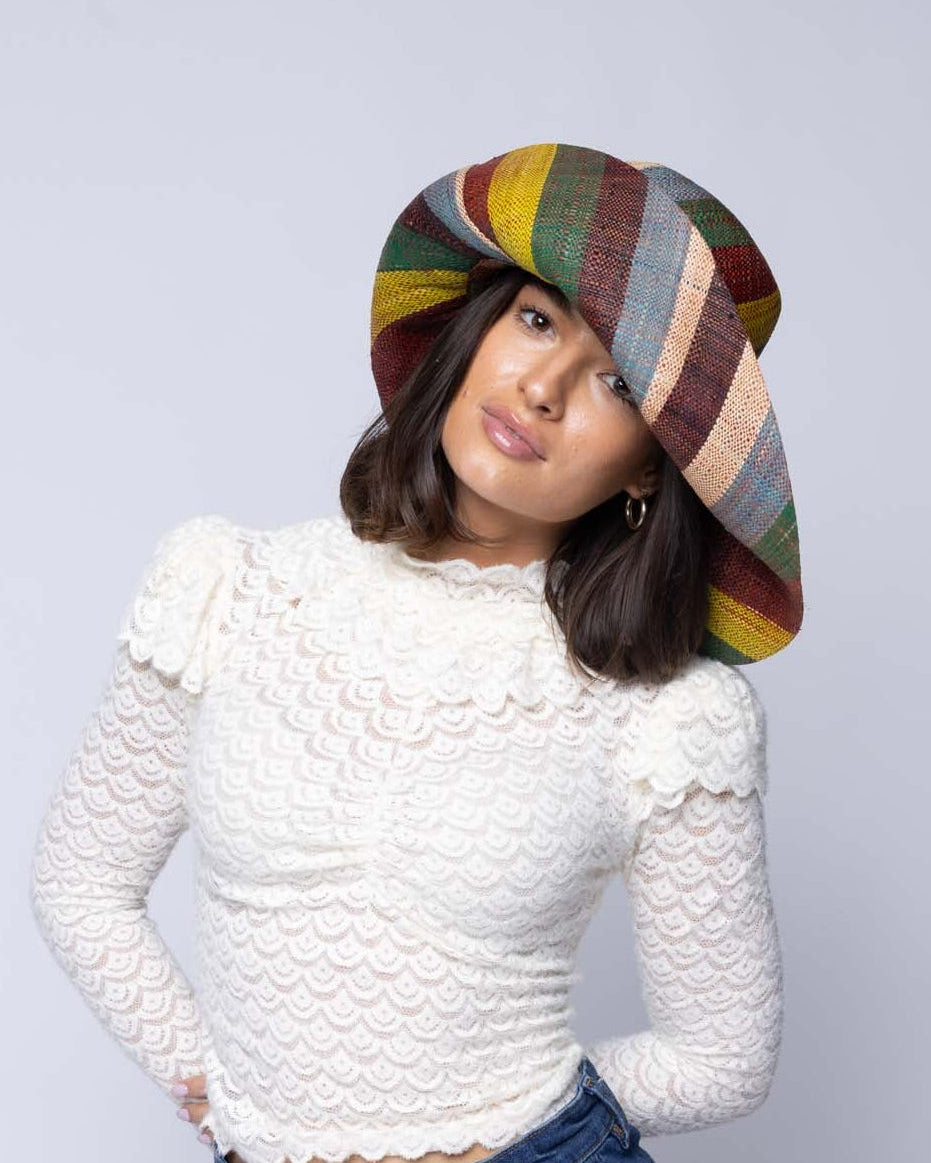 Model wearing Monica 5" & 7" Wide Brim Coral & Blue Swirl Multicolor Stripes Packable Straw Sun Hat Handmade loomed raffia in multi width bands of denim light/blue, whisky caramel/red/brown, black, dark forest/green, midori lime/green, and natural straw color create a swirl pattern - Shebobo