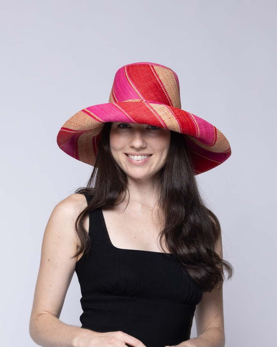 Model wearing Monica 5" & 7" Wide Brim Fuchsia & Red Swirl Multicolor Stripes Packable Straw Sun Hat Handmade loomed raffia in multi width bands of fuchsia hot/bright/pink, red, and natural straw color create a swirl pattern - Shebobo
