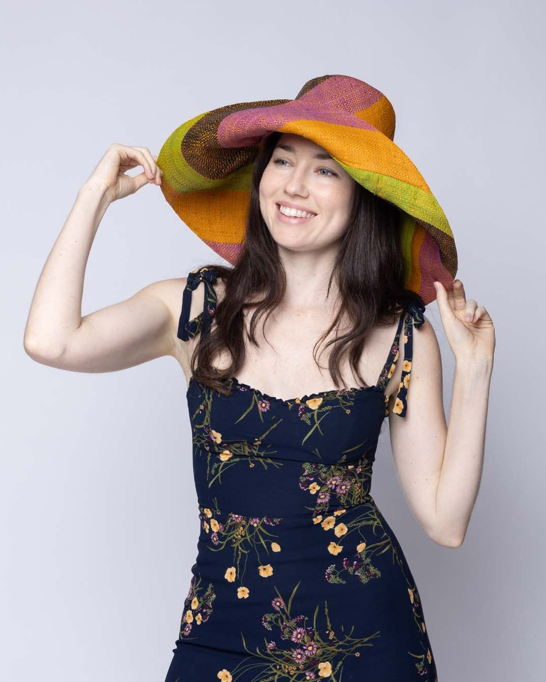 Model wearing Monica 5" & 7" Wide Brim Ipanema Swirl Multicolor Stripes Packable Straw Sun Hat Handmade loomed raffia in multi width bands of saffron yellow/orange, wisteria lilac/light/purple, midori lime/green, black, create a swirl pattern - Shebobo