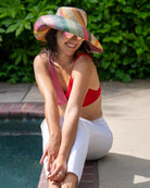 Model wearing Monica 5" Wide Brim Lollipop Multicolor Stripes Packable Straw Sun Hat Handmade loomed raffia in multi width bands of saffron yellow, fuchsia pink, turquoise blue, black, grass green, seafoam blue/green, pink, yellow, orange, blue, red, whiskey brown, natural straw color, etc. create a swirl pattern - Shebobo