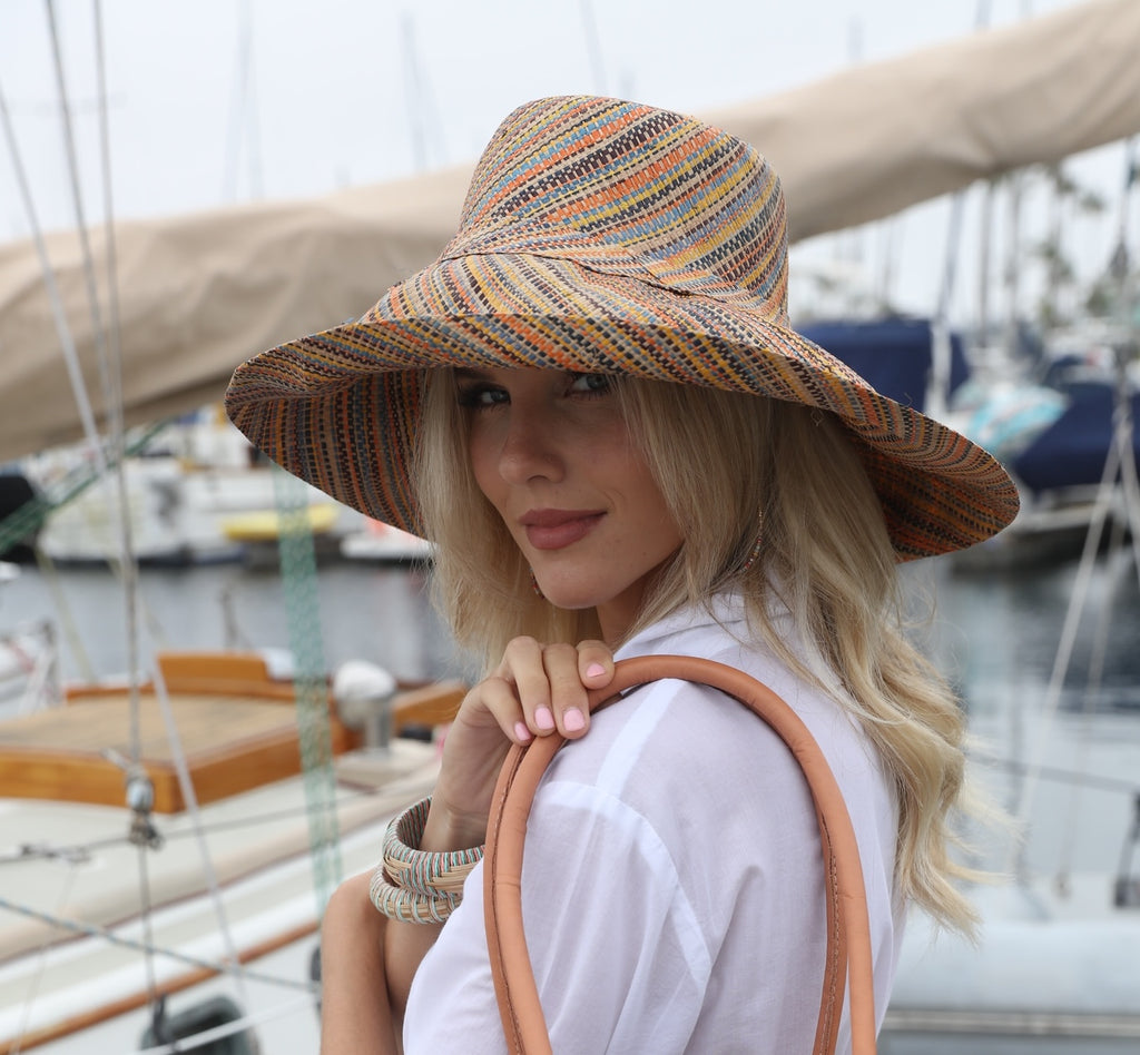 Model wearing Monica 5" Wide Brim Blush Multi Melange Packable Straw Sun Hat handmade loomed raffia multicolor heathered swirl pattern of orange, blush pink, natural, blue, brown, yellow, etc. - Shebobo