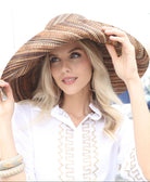 Model wearing Monica 7" Wide Brim Cinnamon Multi Melange Packable Straw Sun Hat handmade loomed raffia in a heathered swirl pattern of multiple tones of natural, brown, and black - Shebobo *dress by Kikisol