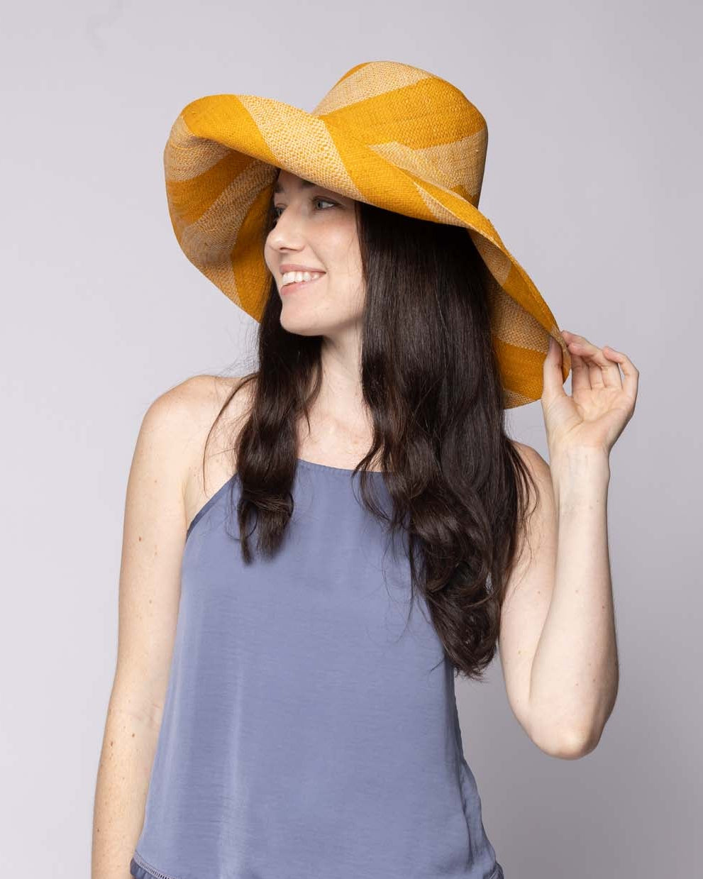 Model wearing Monica 5" & 7" Wide Brim Saffron & Natural Stripe Multicolor Stripes Packable Straw Sun Hat Handmade loomed raffia in even width bands of saffron yellow/orange, and natural straw color create a swirl pattern - Shebobo