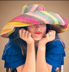 Model wearing Monica 7" Wide Brim Lollipop Multicolor Stripes Packable Straw Sun Hat Handmade loomed raffia in multi width bands of saffron yellow, fuchsia pink, turquoise blue, black, grass green, seafoam blue/green, pink, yellow, orange, blue, red, whiskey brown, natural straw color, etc. create a swirl pattern - Shebobo