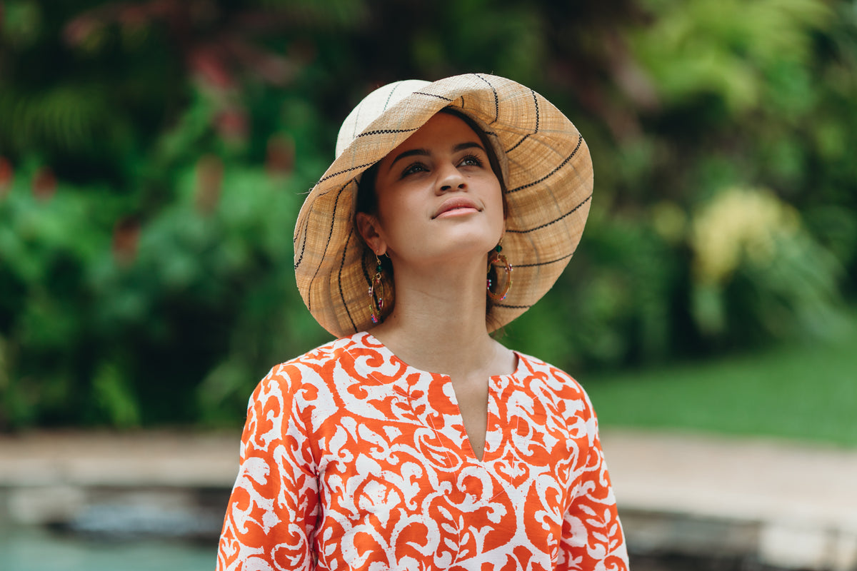 Model wearing Monica 5" wide brim natural and black pinstripes packable raffia straw hat handmade loomed raffia in wide bands of natural straw color with black narrow bands create a stripe swirl pattern - Shebobo