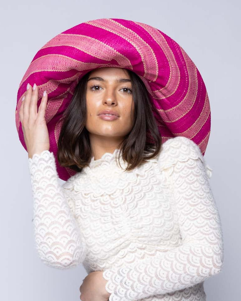 Model wearing Monica 5" & 7" Wide Brim Pink & Fuchsia Swirl Multicolor Stripes Packable Straw Sun Hat Handmade loomed raffia in multi width bands of light pink, fuchsia hot/bright/barbie/pink, natural straw color, etc. create a swirl pattern - Shebobo 