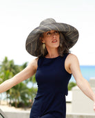 Model wearing Monica 7" Wide Brim Grey Pinstripes Packable Straw Sun Hat handmade loomed raffia in wide bands of grey with narrow bands of natural straw color create a striped swirl pattern - Shebobo