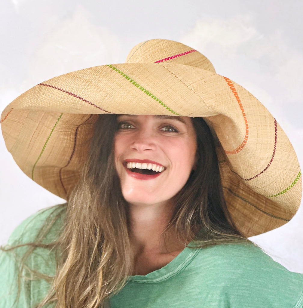 Model wearing Monica 7" wide brim natural and multicolor pinstripes packable raffia straw hat handmade loomed raffia in wide bands of natural straw color with narrow bands of lime green, bordeaux red, fuchsia pink, orange, cinnaon/tobacco/brown, blush orange/pink, etc. create a stripe swirl pattern - Shebobo
