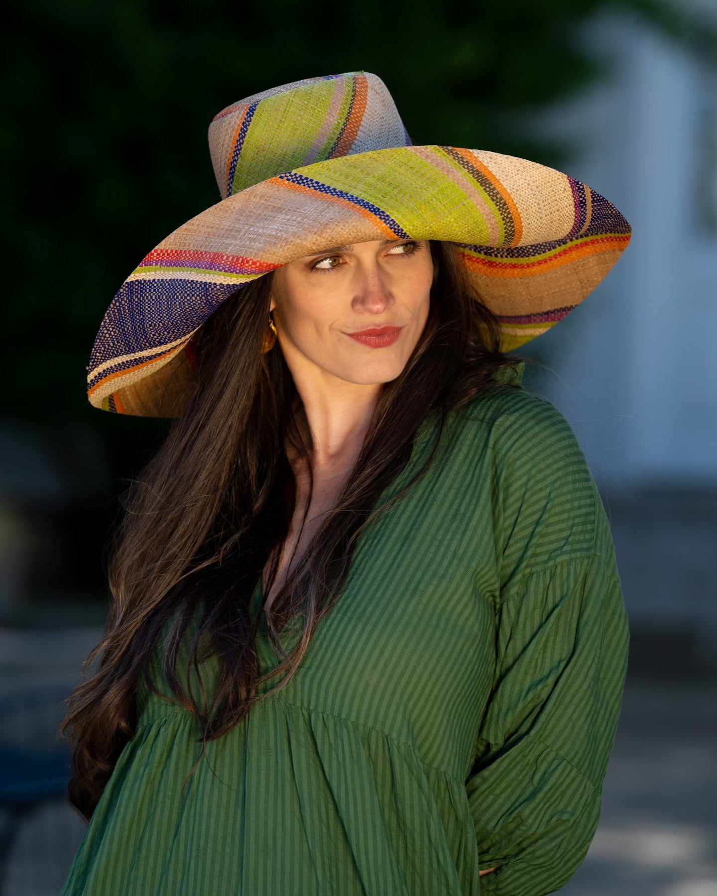 Model wearing Monica 7" Wide Brim Rio Swirl Multicolor Stripes Packable Straw Sun Hat Handmade loomed raffia in multi width bands of cappuccino light brown, lime green, saffron yellow, red, purple, navy blue, natural straw color, etc. create a swirl pattern - Shebobo