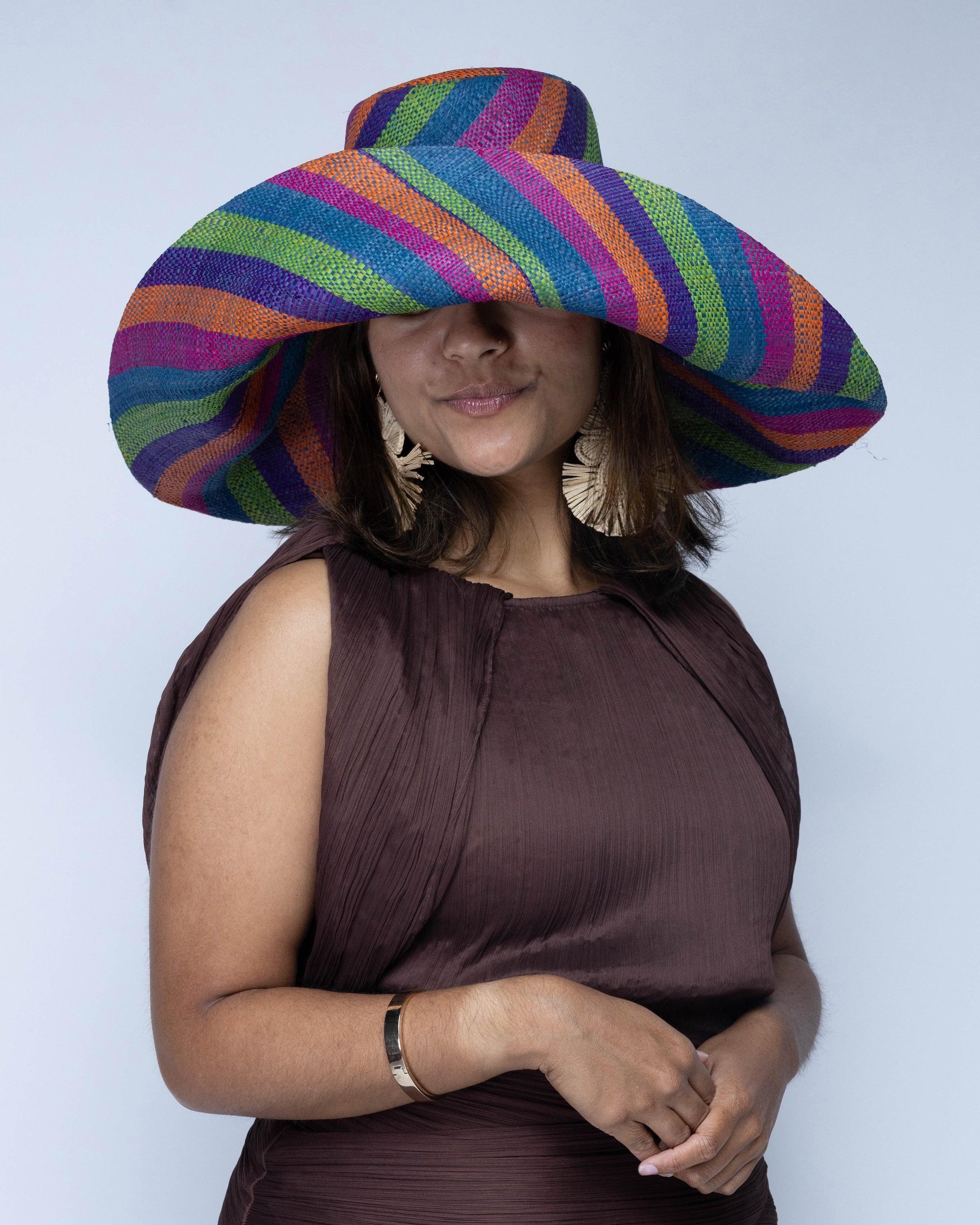 Model wearing Monica 7" Wide Brim Riviera Swirl Multicolor Stripes Packable Straw Sun Hat handmade loomed raffia in bands of fuchsia hot/bright/pink, purple, coral orange/red, midori lime/green, and turquoise blue stripes create a swirl pattern - Shebobo