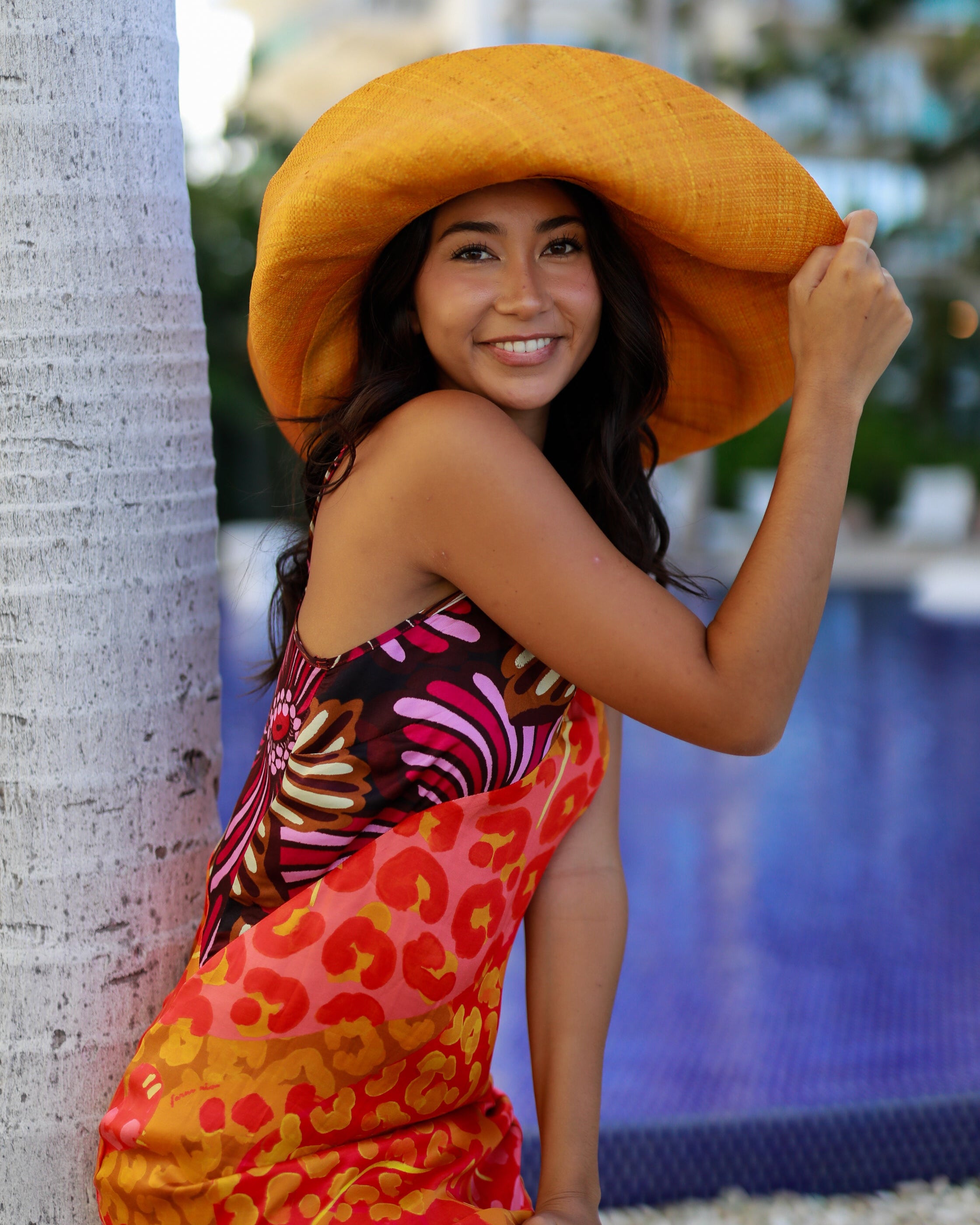 Model wearing Monica 7" Wide Brim Solid Color Packable Straw Sun Hat handmade loomed raffia in a solid hue of saffron yellow/orange - Shebobo