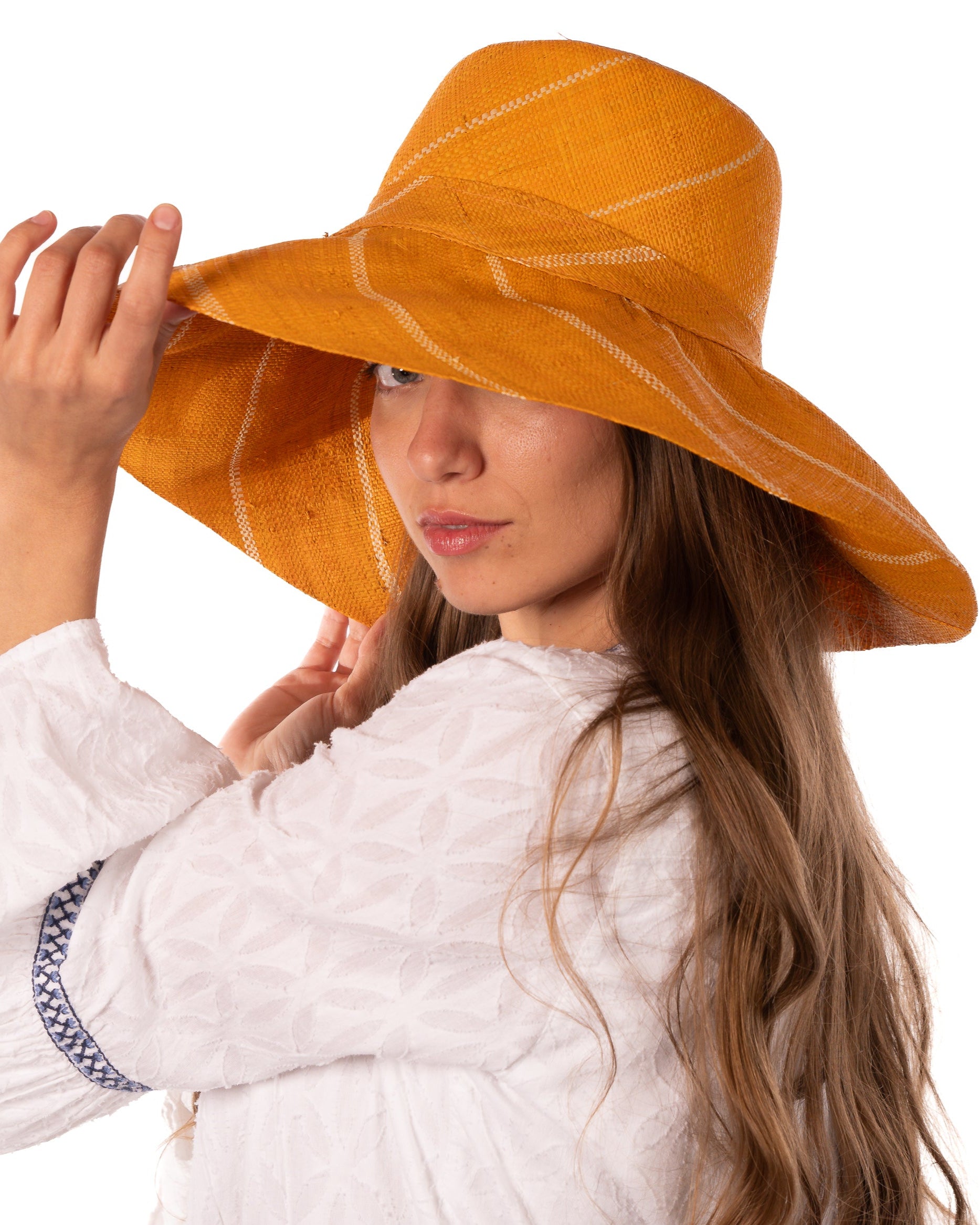 Model wearing Monica 5" Wide Brim Saffron Pinstripes Packable Straw Sun Hat handmade loomed raffia in wide stripes of saffron yellow/orange with narrow stripes of natural creating a swirl pattern - Shebobo
