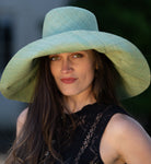 Model wearing Monica 7" Wide Brim Seafoam Packable Straw Sun Hat handmade loomed raffia in a solid hue of seafoam light/green/blue lightweight malleable flexible sun protection hat - Shebobo