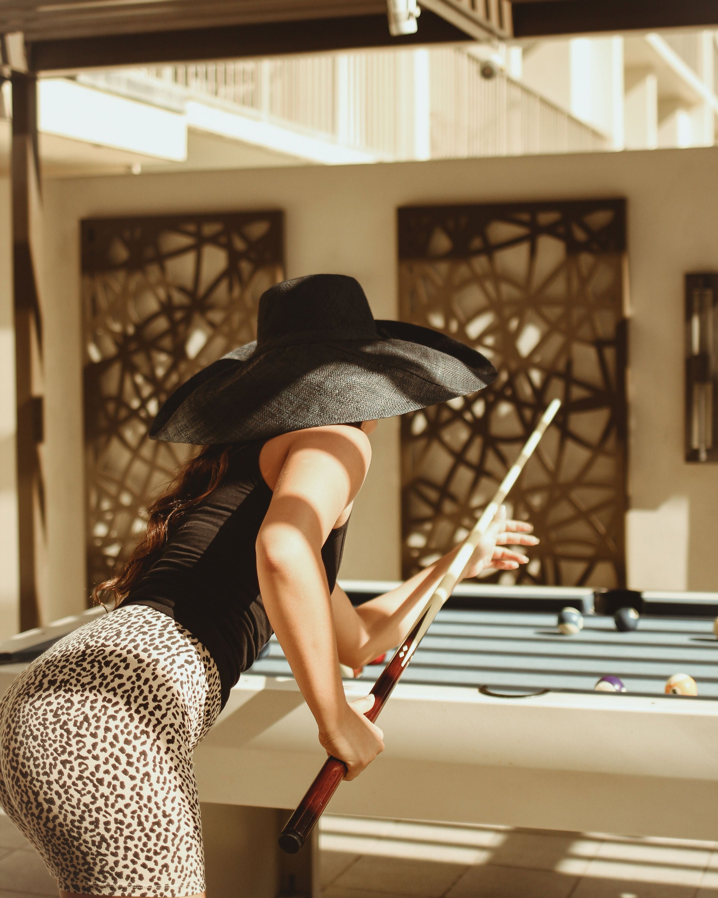 Model wearing Monica 7" Wide Brim Solid Color Packable Straw Sun Hat handmade loomed raffia in a solid hue of black - Shebobo