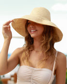 Model wearing Monica 5" wide brim natural loomed raffia shapeable packable straw hat handmade loomed raffia in a solid hue of natural straw color - Shebobo