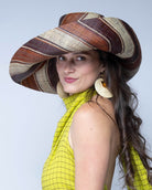 Model wearing Monica 7" Wide Brim Tawny Swirl Multicolor Stripes Packable Straw Sun Hat handmade loomed raffia in bands of natural straw color, mocha dark/chocolate/brown, and tobacco cinnamon/dark/brown stripes create a swirl pattern - Shebobo