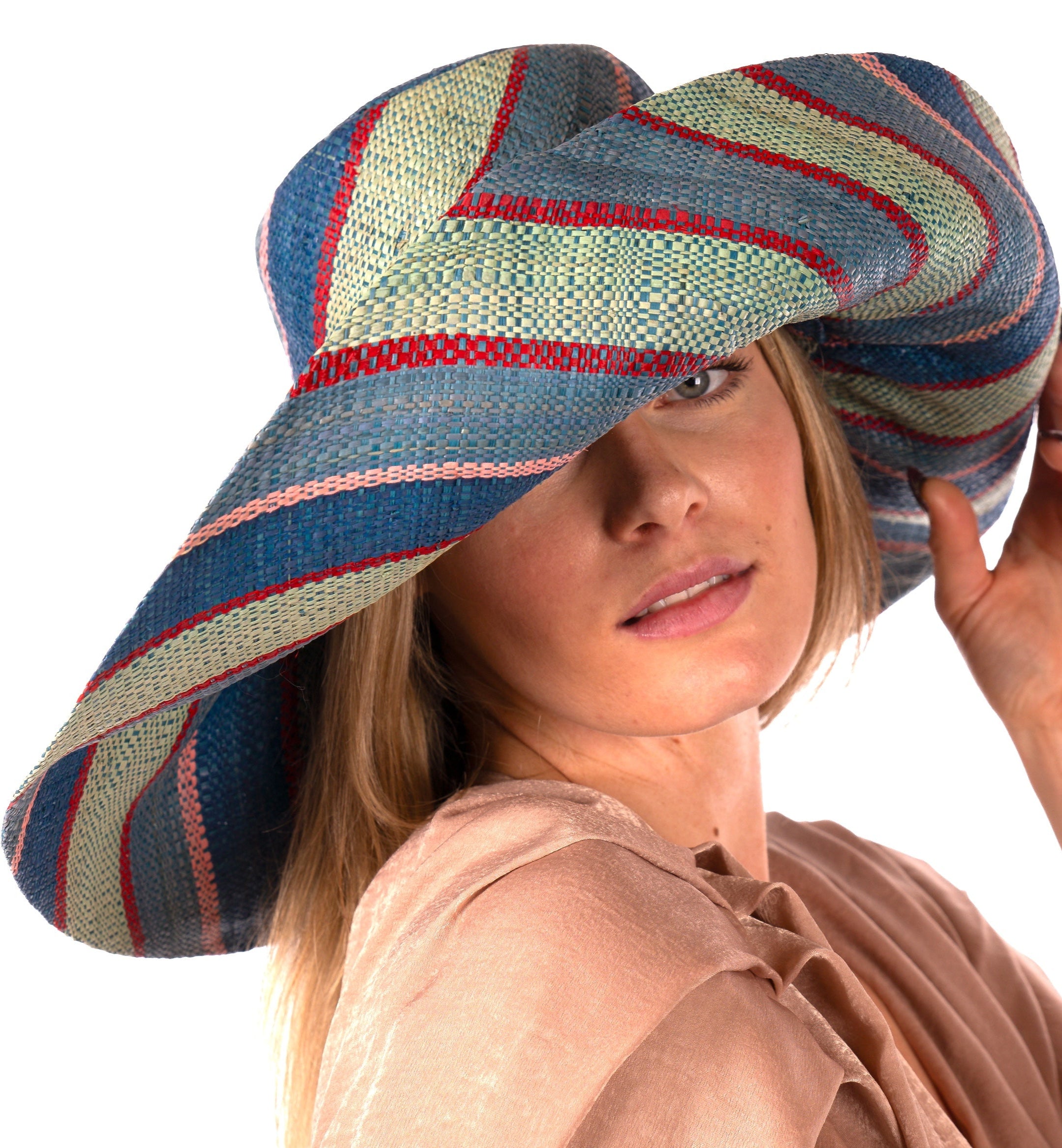 Model wearing Monica 7" Wide Brim Teal Swirl Multicolor Stripes Packable Straw Sun Hat Handmade loomed raffia in multi width bands of teal blue/green, seafoam green/blue, red, and pink create a swirl pattern - Shebobo