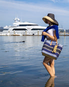 Model wearing Monica 7" Wide Brim Two Tone Black Packable Straw Sun Hat handmade loomed raffia color block pattern of the top half black and the bottom half natural straw color - Shebobo (with Cabrillo Blue Multi Stripe Sisal Basket Bag)