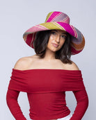 Model wearing 5" & 7" Wide Brim Zazzleberry Swirl Multicolor Stripes Packable Straw Sun Hat Handmade loomed raffia in multi width bands of fuchsia hot/bright/pink, light blue, light pink, red, orange, lime green, denim grey/blue, turquoise, and natural straw color create a swirl pattern - Shebobo