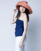 Model wearing Monica 7" Wide Brim Solid Color Packable Straw Sun Hat handmade loomed raffia in a solid hue of Blush orange/terracotta/pink  - Shebobo