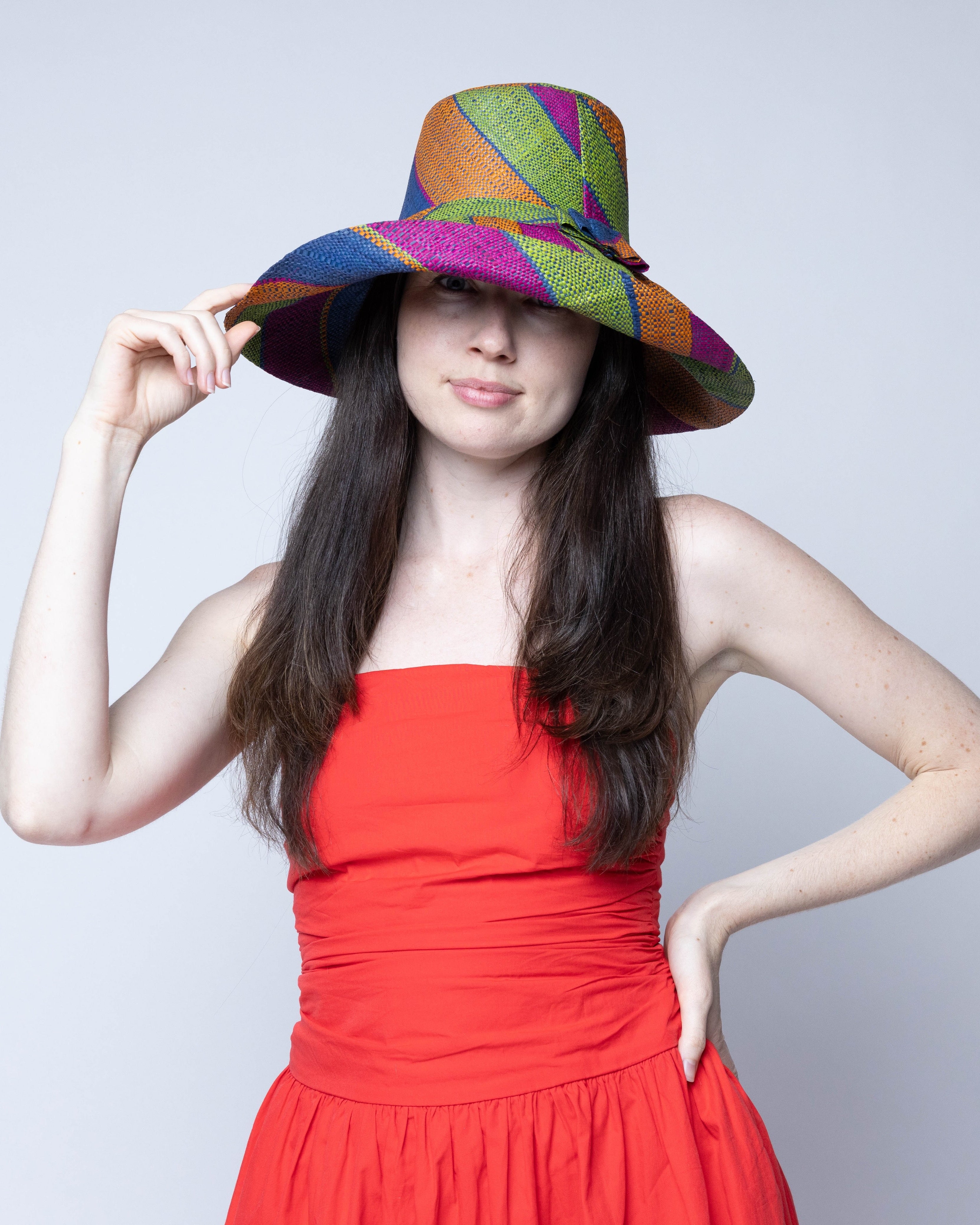 Model wearing Monica 5" Wide Brim Caribbean Swirl Multicolor Stripes Packable Straw Sun Hat Handmade loomed raffia in multi width bands of fuchsia pink, orange, dusk navy/dark/blue, and lime green create a swirl pattern - Shebobo