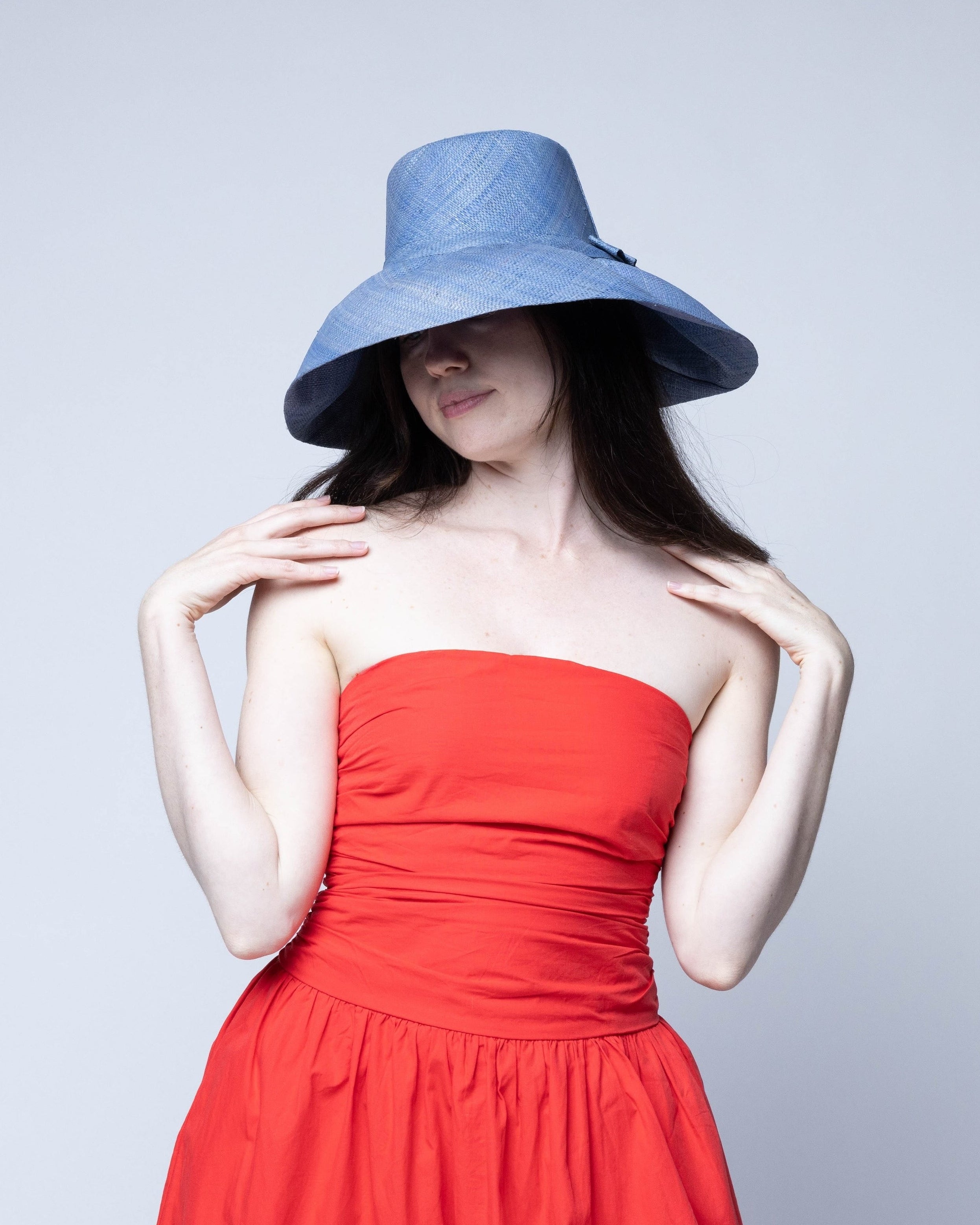 Model wearing Monica 5" Wide Brim Denim Packable Straw Sun Hat handmade loomed raffia in a solid hue of denim retro/light/blue lightweight malleable flexible sun protection hat - Shebobo