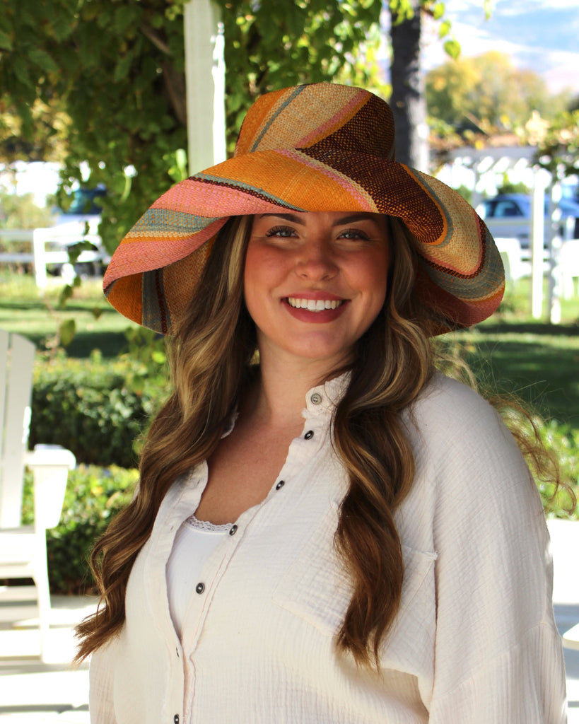 Model wearing Monica 5" Wide Brim Pink Blue Swirl Multicolor Stripes Packable Straw Sun Hat Handmade loomed raffia in multi width bands of saffron yellow, light pink, light blue, black, natural straw color etc. create a swirl pattern - Shebobo